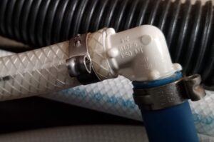 Image of RV water line 90 degree elbow with nylon braided hose and blue pex piping